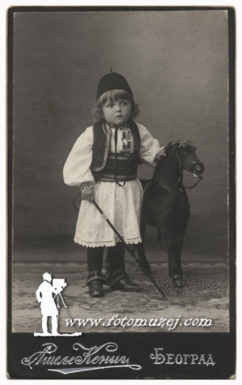 Dečak u šumadijskom odelu sa drvenim konjićem (Atelje Kenig)